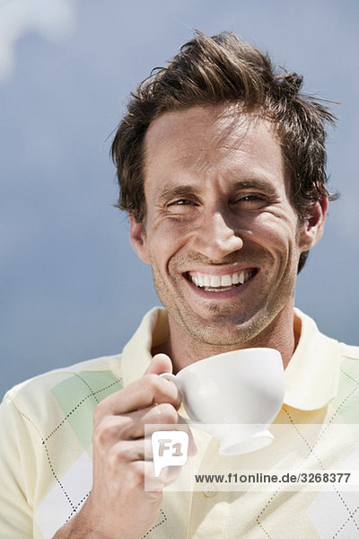 Italien  Südtirol  Mann hält Tasse Kaffee  draußen  lachend  Portrait  Nahaufnahme