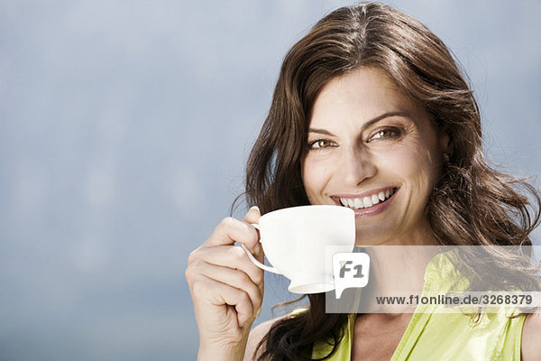 Italien  Südtirol  Frau bei einer Tasse Kaffee  draußen  lächelnd  Portrait  Nahaufnahme