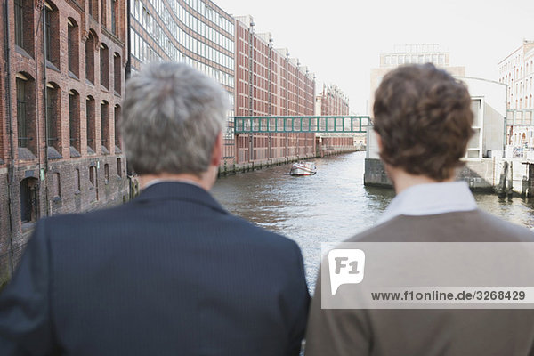Deutschland,  Hamburg,  Zwei Geschäftsleute mit Blick über den Kanal,  Rückansicht