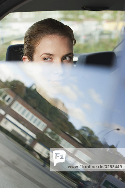 Geschäftsfrau im Auto sitzend,  aus dem Fenster schauend,  Porträt