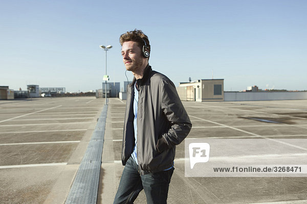 Young man on deserted parking level wearing headphones