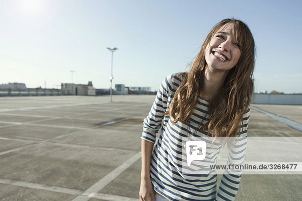 Young woman on parking level  laughing  portrait