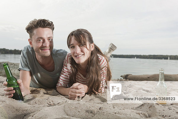 Germany  Berlin  Lake Wannsee  Young couple lying on beach  smiling  portrait