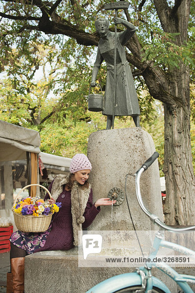 Viktualienmarkt  Frau am Brunnen sitzend  Blumenkorb haltend