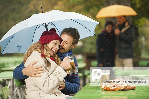 Deutschland  Bayern  Englischer Garten  Vier Personen im regnerischen Biergarten