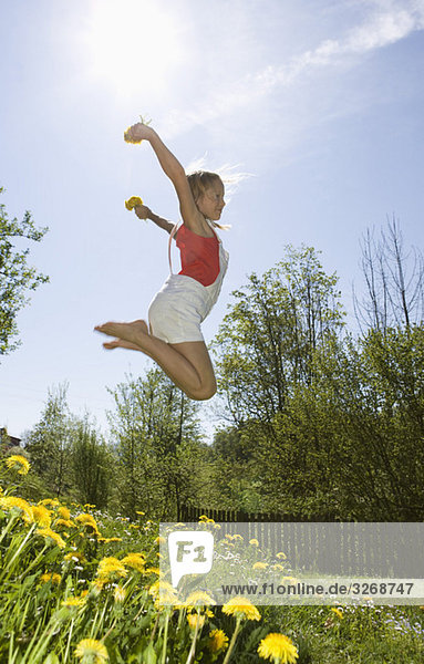 Austria  Salzkammergut  girl (10-11) jumping in garden  side view