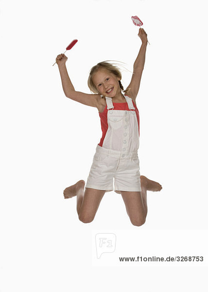 Mädchen (10-11) hält Lutscher  springt in die Luft  lächelt  Portrait