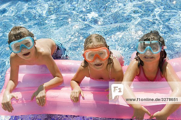 Drei Kinder auf einer Hüpfburg im Pool