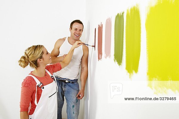 Frau malt Farbmuster an die Wand