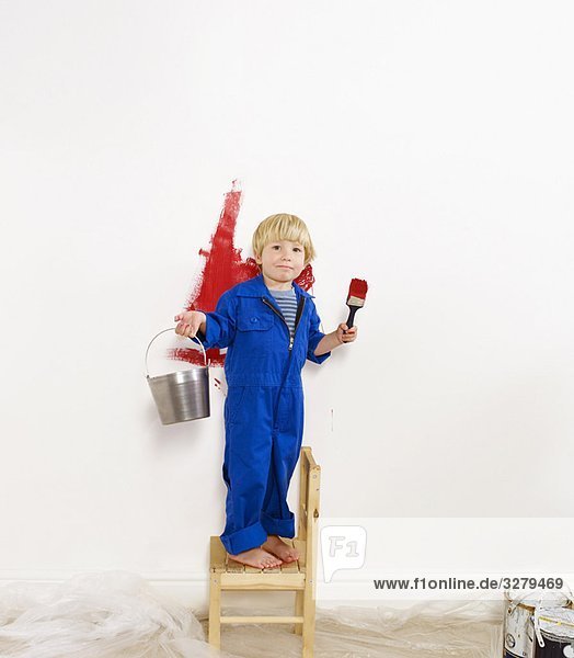 Kleinkind Junge malt Wand rot.
