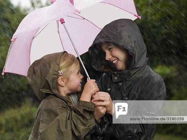 Mädchen unter einem Schirm zusammengekauert