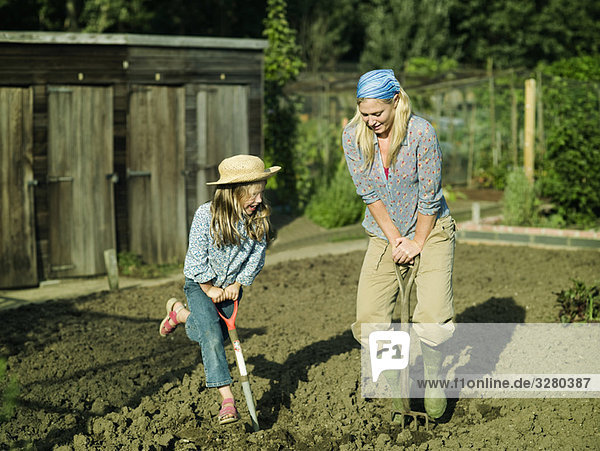 Eine Frau und ein Mädchen graben einen Garten.