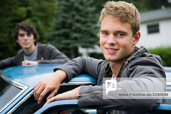 Two young men by car