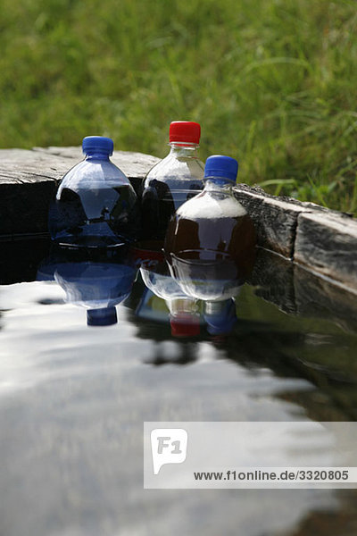 Plastikflaschen mit Soda  die in einen Wassertrog getaucht sind.