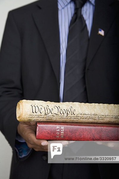 Detail eines Mannes  der eine Bibel und eine Schriftrolle der amerikanischen Verfassung hält.
