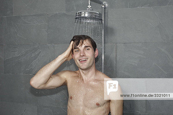 Ein Mann  der unter einer Dusche steht.