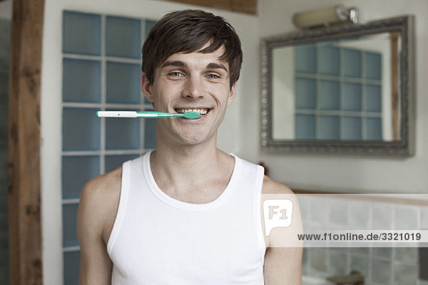 Ein Mann beißt auf eine Zahnbürste und lächelt.