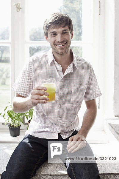 A man holding a glass of juice and smiling