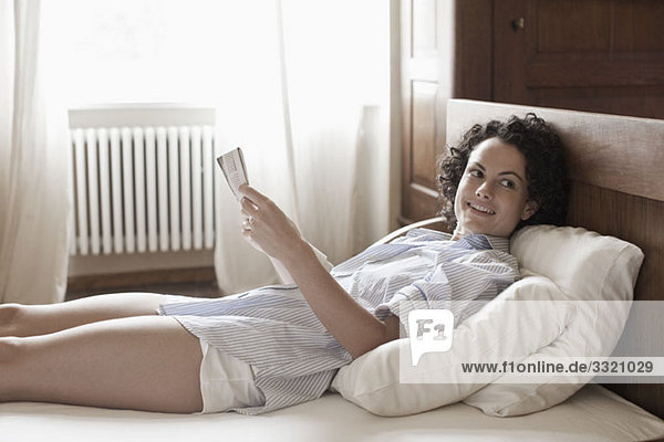 A woman lying down and reading on her bed