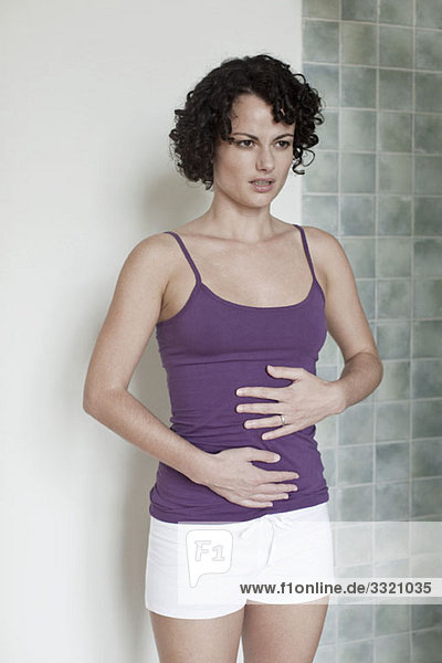 A woman standing touching her stomach