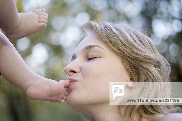 Eine Mutter  die die Zehen ihres Babys küsst.