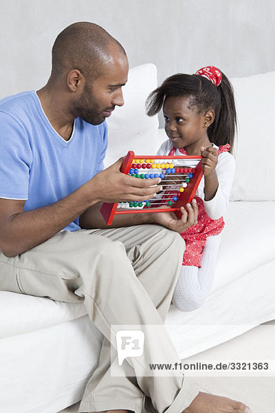 A father showing his young daughter how to use an abacus