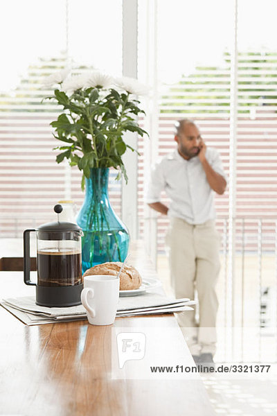 Breakfast on a kitchen counter and a man using a phone in the background
