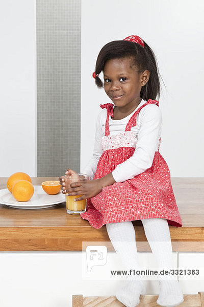 A young girl holding a glass of orange juice  portrait