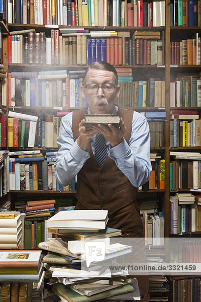 A man blowing dust off an old book