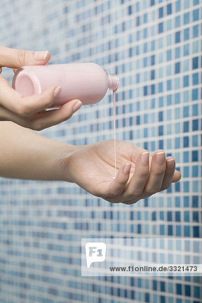 Eine Frau  die Feuchtigkeitscreme in ihre Handfläche gießt  Nahaufnahme der Hände