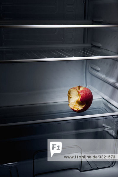 Ein halb gegessener Apfel im leeren Kühlschrank