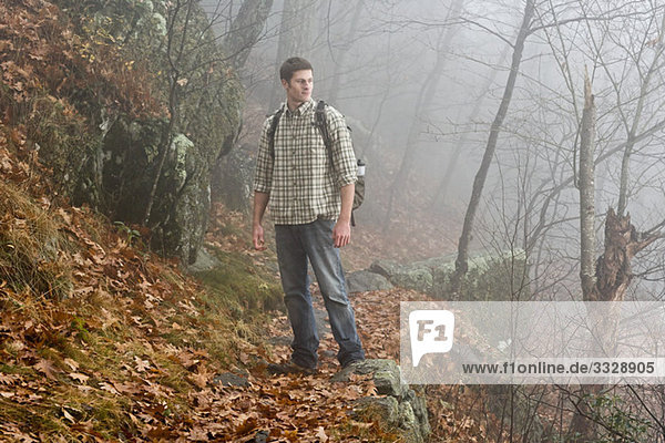 A male hiker explores a misty forest