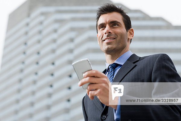 Ein Geschäftsmann lächelt  während er ein Handy in der Hand hält.