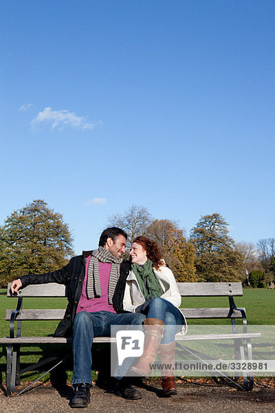Ein Paar sitzt von Angesicht zu Angesicht auf einer Parkbank.