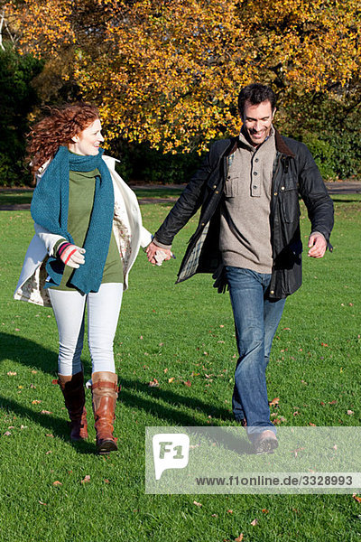 Ein mittleres erwachsenes Paar hält sich im Dulwich Park an den Händen.