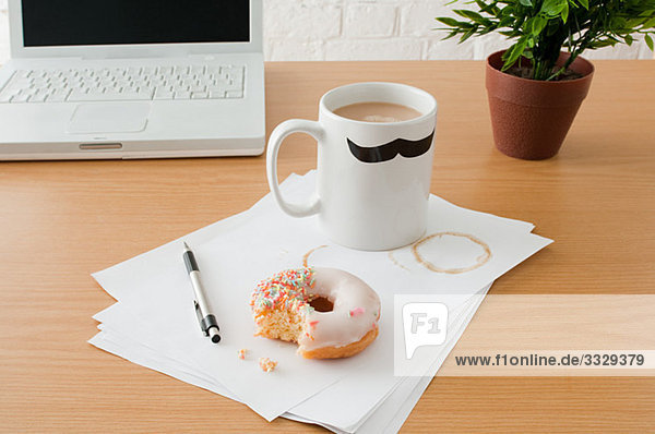 Kaffee und Doughnut auf dem Schreibtisch