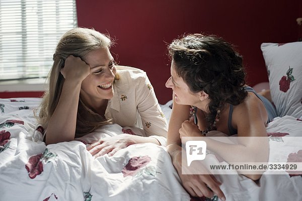 two women laying on bed talking
