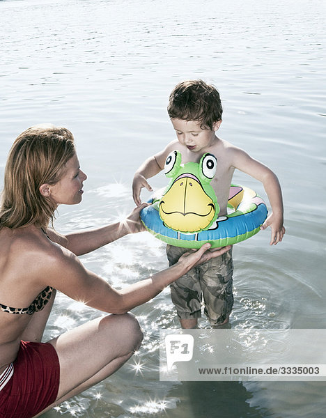Mother fitting child's swimming ring
