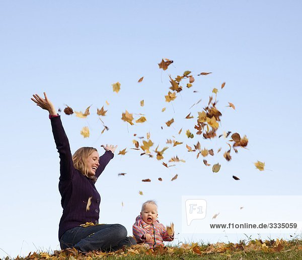 mother and baby throwing autumn leaves