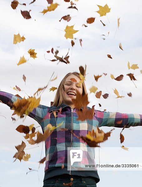 Mädchen wirft Herbstlaub in die Luft