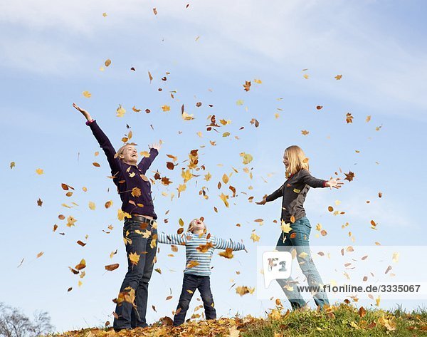 woman  boy and girl throw autumn leaves
