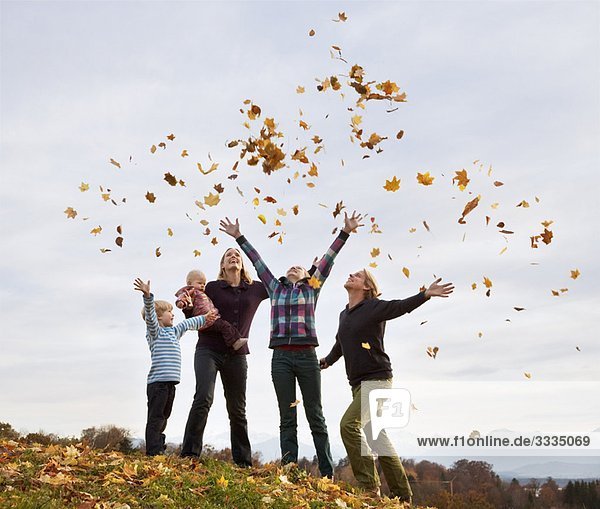 family throwing autumn leaves into air