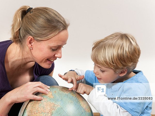 mother and son study globe