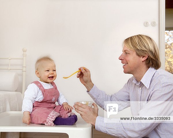 Vater füttert Baby