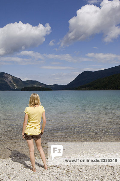 A young woman standing by a lake