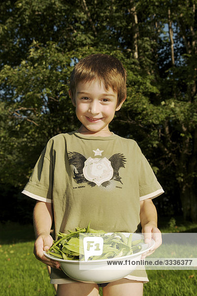 lächelnder Junge in T-shirt hält Schüssel der Erbse Hülsen  Maricourt  Québec