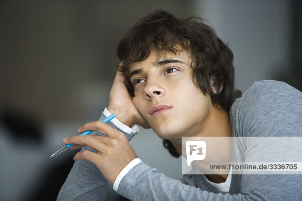 Young man leaning on elbow idly looking away