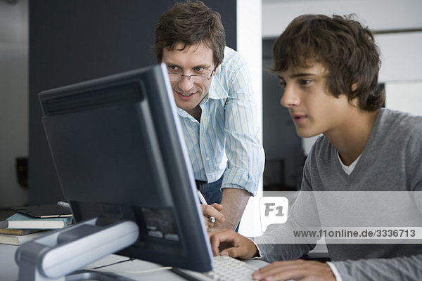Lehrer lächelt  überprüft die Arbeit der Schüler am Computer