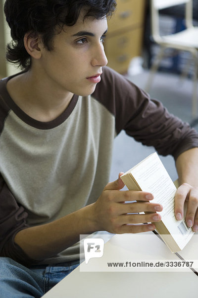 Male high school student in class  holding book