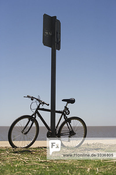 Bicycle leaning against street sign  beach in background